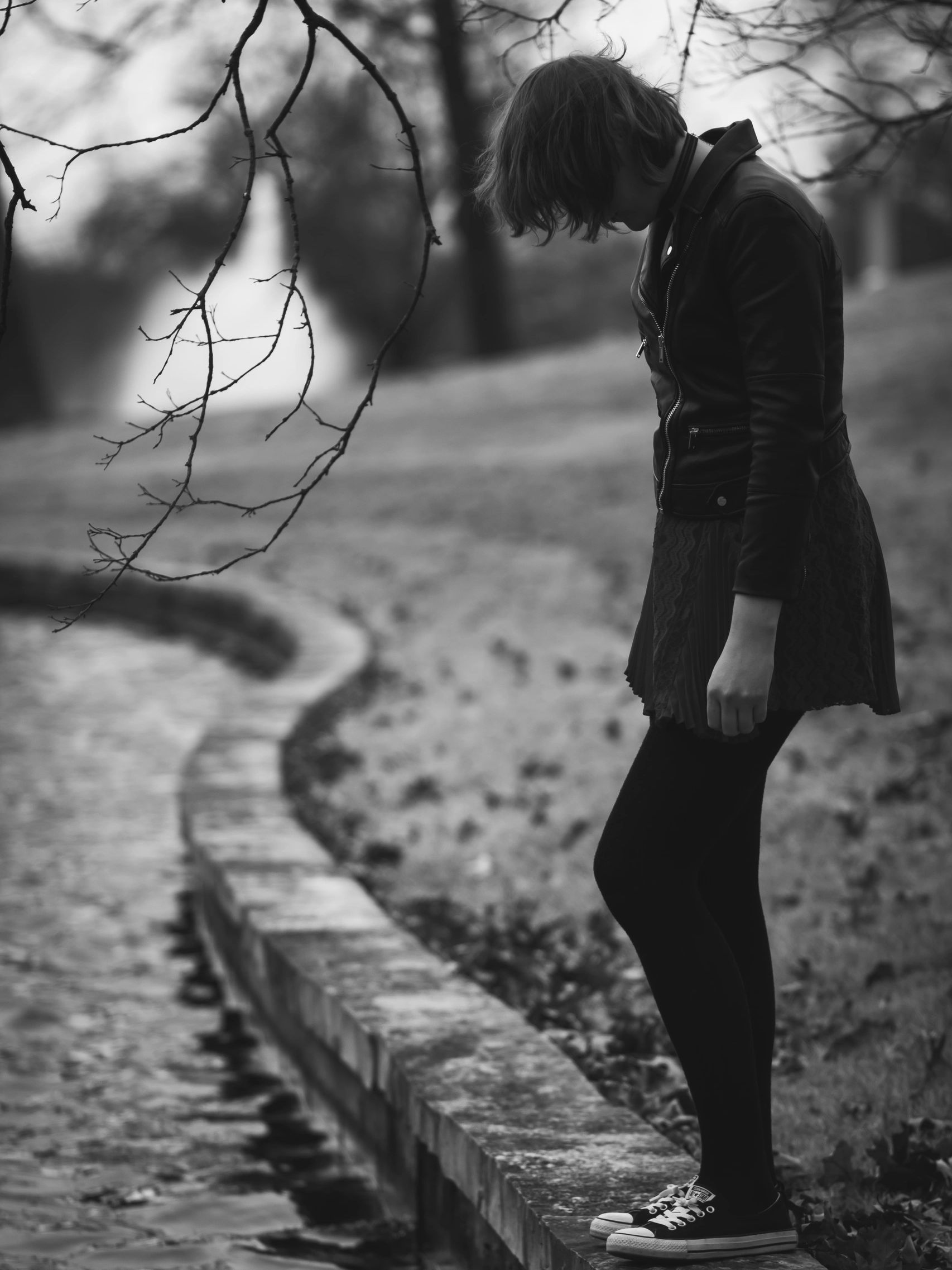 Person on stone ledge with bare branches